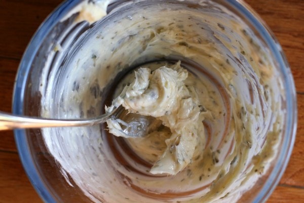 Herbs and butter mixed in a glass bowl.